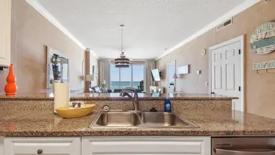 a kitchen with a sink and a view of the ocean at Emerald Isle 403 by Emerald Coast Retreats in Panama City Beach