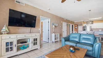 a living room with a tv and a couch and a table at Emerald Isle 403 by Emerald Coast Retreats in Panama City Beach