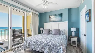 a bedroom with a bed and a balcony with the ocean at Emerald Isle 403 by Emerald Coast Retreats in Panama City Beach