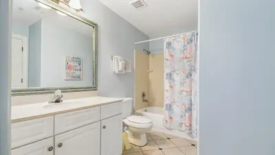 a bathroom with a sink and a toilet and a mirror at Emerald Isle 403 by Emerald Coast Retreats in Panama City Beach