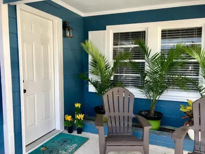 a blue room with a chair and palm trees at Surf Shack - Steps to the beach, lush fenced backyard by Beach Haven Vacation Rentals in Panama City Beach