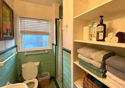 a bathroom with a toilet and some towels and a window at Surf Shack - Steps to the beach, lush fenced backyard by Beach Haven Vacation Rentals in Panama City Beach