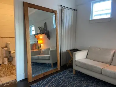 a living room with a mirror and a couch at Surf Shack - Steps to the beach, lush fenced backyard by Beach Haven Vacation Rentals in Panama City Beach