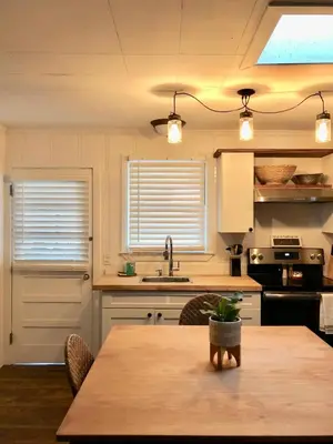 a kitchen with a wooden table and a kitchen with a sink at Surf Shack - Steps to the beach, lush fenced backyard by Beach Haven Vacation Rentals in Panama City Beach