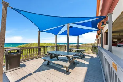a patio with two picnic tables and a trash can at Sunrise Beach - 1610 by Beach Haven Vacation Rentals in Panama City Beach