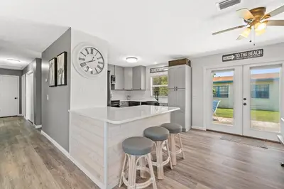 a kitchen with a clock on the wall and stools at Sunny Daze Cottage by Beach Haven Vacation Rentals in Panama City Beach