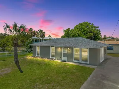 a house with a palm tree in the yard at Sunny Daze Cottage by Beach Haven Vacation Rentals in Panama City Beach