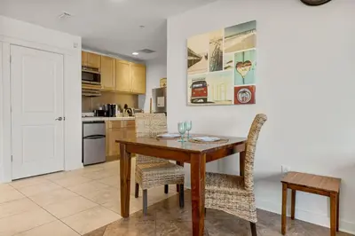 a kitchen and dining room with a wooden table and chairs at Origin 0609 - Studio King - Beautiful Sunset Gulf Views! by Beach Haven Vacation Rentals in Panama City Beach