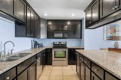 a kitchen with black cabinets and a stove top oven at Sharkys Retreat 701 by Beach Haven Vacation Rentals in Panama City Beach