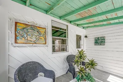 a porch with two chairs and a painting of a fish at Sea Shed by Beach Haven Vacation Rentals in Panama City Beach