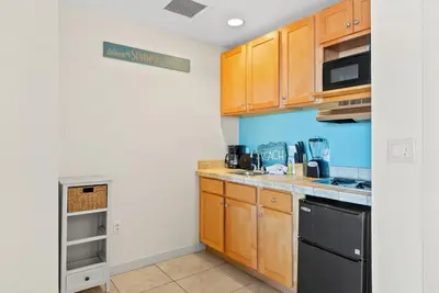 a kitchen with wooden cabinets and black appliances at Origin 1329 - Studio King Gulf View - Sunrise Views by Beach Haven Vacation Rentals in Panama City Beach