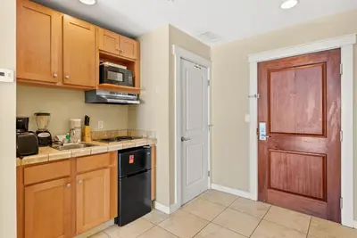 a kitchen with wooden cabinets and a black dishwasher at Origin 1320 - Studio King Gulf View- Amazing Gulf View by Beach Haven Vacation Rentals in Panama City Beach