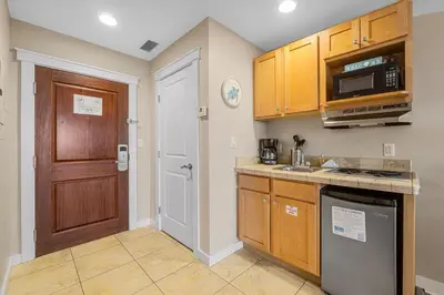 a kitchen with wooden cabinets and a door at Origin 1313 - Studio King - Amazing Value - Cozy Unit by Beach Haven Vacation Rentals in Panama City Beach