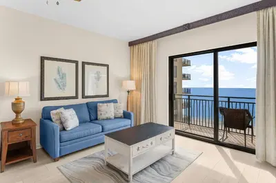a living room with a blue couch and a balcony at Origin 1220 - Studio King - Gulf View by Beach Haven Vacation Rentals in Panama City Beach