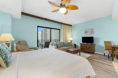 a bedroom with a large bed and a living room at Origin 1129 - Studio King Gulf View - Partial Gulf View by Beach Haven Vacation Rentals in Panama City Beach