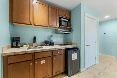 a kitchen with wooden cabinets and a sink and a microwave at Origin 1129 - Studio King Gulf View - Partial Gulf View by Beach Haven Vacation Rentals in Panama City Beach
