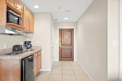 a kitchen with wooden cabinets and a black dishwasher at Origin 1125 - Studio King - Peaceful Nature View Unit by Beach Haven Vacation Rentals in Panama City Beach