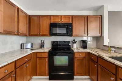 a kitchen with wooden cabinets and a black stove top oven at Origin 1116 - One Bedroom - Beautiful Gulf View by Beach Haven Vacation Rentals in Panama City Beach