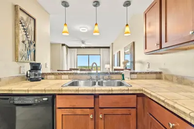 a kitchen with wooden cabinets and a sink at Origin 1111 - One Bedroom - Cozy Partial Gulf View by Beach Haven Vacation Rentals in Panama City Beach
