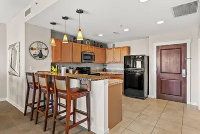 a kitchen with wooden cabinets and a island with bar stools at Origin 1107- One Bedroom - Gorgeous Gulf & Sunset Views by Beach Haven Vacation Rentals in Panama City Beach