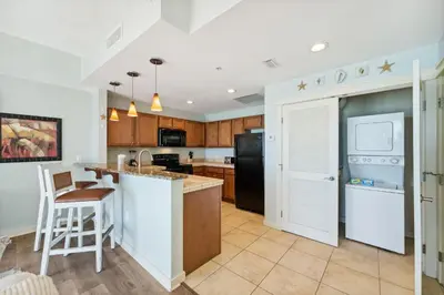 a kitchen with a counter and a bar with a stool at Origin 1024 - One Bedroom - Sunny Pool Deck & Gulf Views by Beach Haven Vacation Rentals in Panama City Beach