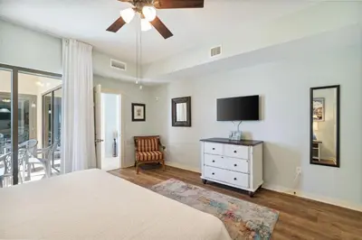 a bedroom with a bed and a tv and a chair at Origin 1024 - One Bedroom - Sunny Pool Deck & Gulf Views by Beach Haven Vacation Rentals in Panama City Beach