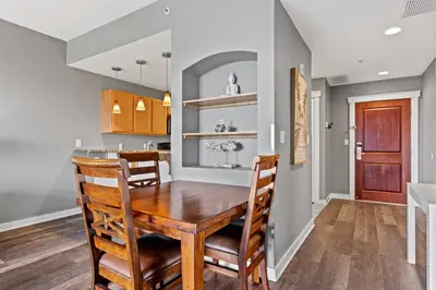 a dining room and kitchen with a wooden table and chairs at Origin 1011 - One Bedroom - Spacious Partial Gulf View by Beach Haven Vacation Rentals in Panama City Beach