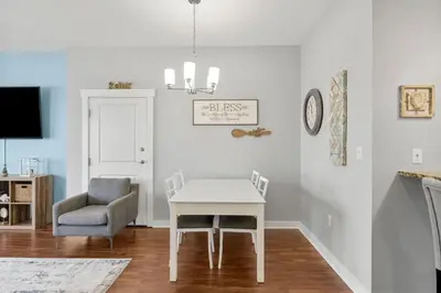 a dining room with a white table and a chair at Origin 1007 - One Bedroom - Sunset View by Beach Haven Vacation Rentals in Panama City Beach