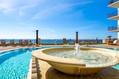 a fountain in a pool with the ocean in the background at Origin 1007 - One Bedroom - Sunset View by Beach Haven Vacation Rentals in Panama City Beach