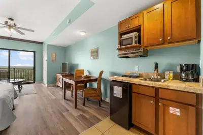 a kitchen and living room with a table and a microwave at Origin 0915 - Studio King - Cozy Nature View by Beach Haven Vacation Rentals in Panama City Beach