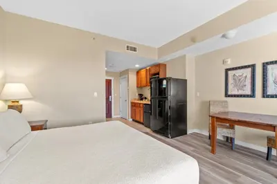 a bedroom with a bed and a desk and a refrigerator at Origin 0833 - Studio King - Sunrise & Gulf View by Beach Haven Vacation Rentals in Panama City Beach