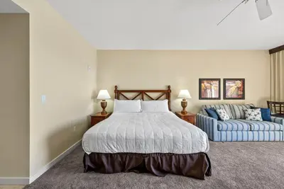 a bedroom with a bed and a blue couch at Origin 0820 - Studio King - Stunning Gulf Views by Beach Haven Vacation Rentals in Panama City Beach