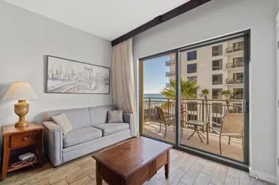 a living room with a couch and a balcony at Origin 0734 - Studio King - Sunny Pool Deck and Gulf View by Beach Haven Vacation Rentals in Panama City Beach
