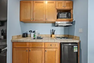 a kitchen with wooden cabinets and a stove top oven at Origin 0729 - Studio King - Sunrise Gulf View by Beach Haven Vacation Rentals in Panama City Beach
