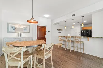a kitchen and dining room with a wooden table and chairs at Origin 0708 - One Bedroom - Pool and Gulf Views by Beach Haven Vacation Rentals in Panama City Beach