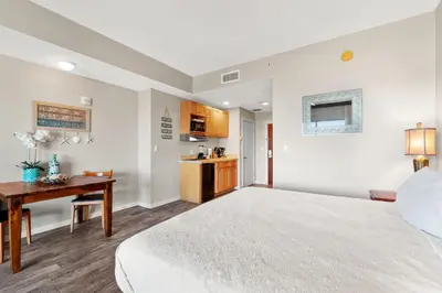 a bedroom with a bed and a desk and a kitchen at Origin 0705 - Studio King Gulf View- Stunning Sunset Views by Beach Haven Vacation Rentals in Panama City Beach