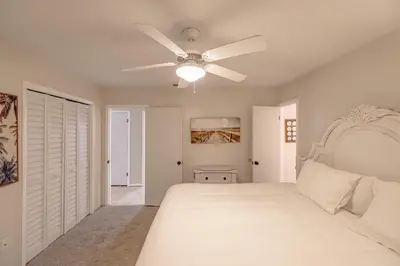 a bedroom with a white bed and a ceiling fan at Boat dock and jet ski pad! bring your boat! in Panama City Beach
