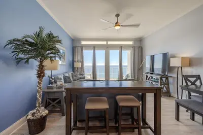 a living room with a dining room table with a palm tree at Laketown - Top Floor! Amazing Views! in Panama City Beach