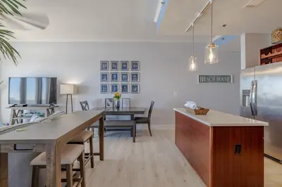 a kitchen and dining room with a table and a refrigerator at Laketown - Top Floor! Amazing Views! in Panama City Beach