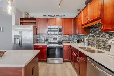 a kitchen with wooden cabinets and stainless steel appliances at Laketown - Top Floor! Amazing Views! in Panama City Beach