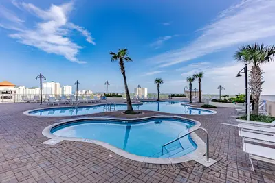 a swimming pool with palm trees in a resort at Laketown - Top Floor! Amazing Views! in Panama City Beach