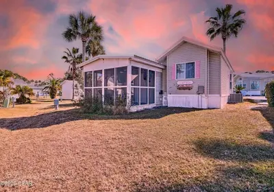 a white house with palm trees in a yard at Enjoy your quiet vacation at Butler's Beach Retreat! in Panama City Beach