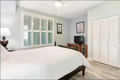 a bedroom with a white bed and a television at Aqua 403 - Free Beach Chairs! Indoor/Outdoor Pool! in Panama City Beach