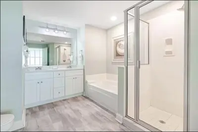 a bathroom with a shower and a tub and a sink at Aqua 403 - Free Beach Chairs! Indoor/Outdoor Pool! in Panama City Beach