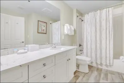 a white bathroom with a sink and a toilet at Aqua 403 - Free Beach Chairs! Indoor/Outdoor Pool! in Panama City Beach