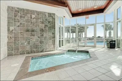 an indoor swimming pool in a home with a large wall of windows at Aqua 403 - Free Beach Chairs! Indoor/Outdoor Pool! in Panama City Beach