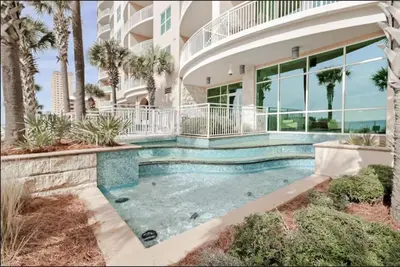 a house with a swimming pool in front of a building at Aqua 403 - Free Beach Chairs! Indoor/Outdoor Pool! in Panama City Beach