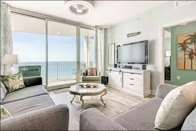 a living room with a couch and a tv at Aqua 403 - Free Beach Chairs! Indoor/Outdoor Pool! in Panama City Beach