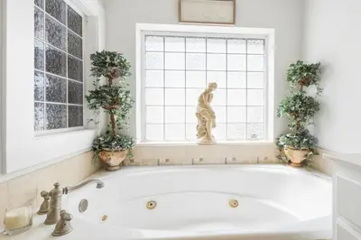 a bath tub in a bathroom with a statue in a window at Sandy Shenanigans by Blu Skye! -New to Management 2025! in Panama City Beach