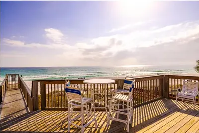 a deck with a table and chairs and the ocean at Sandy Shenanigans by Blu Skye! -New to Management 2025! in Panama City Beach